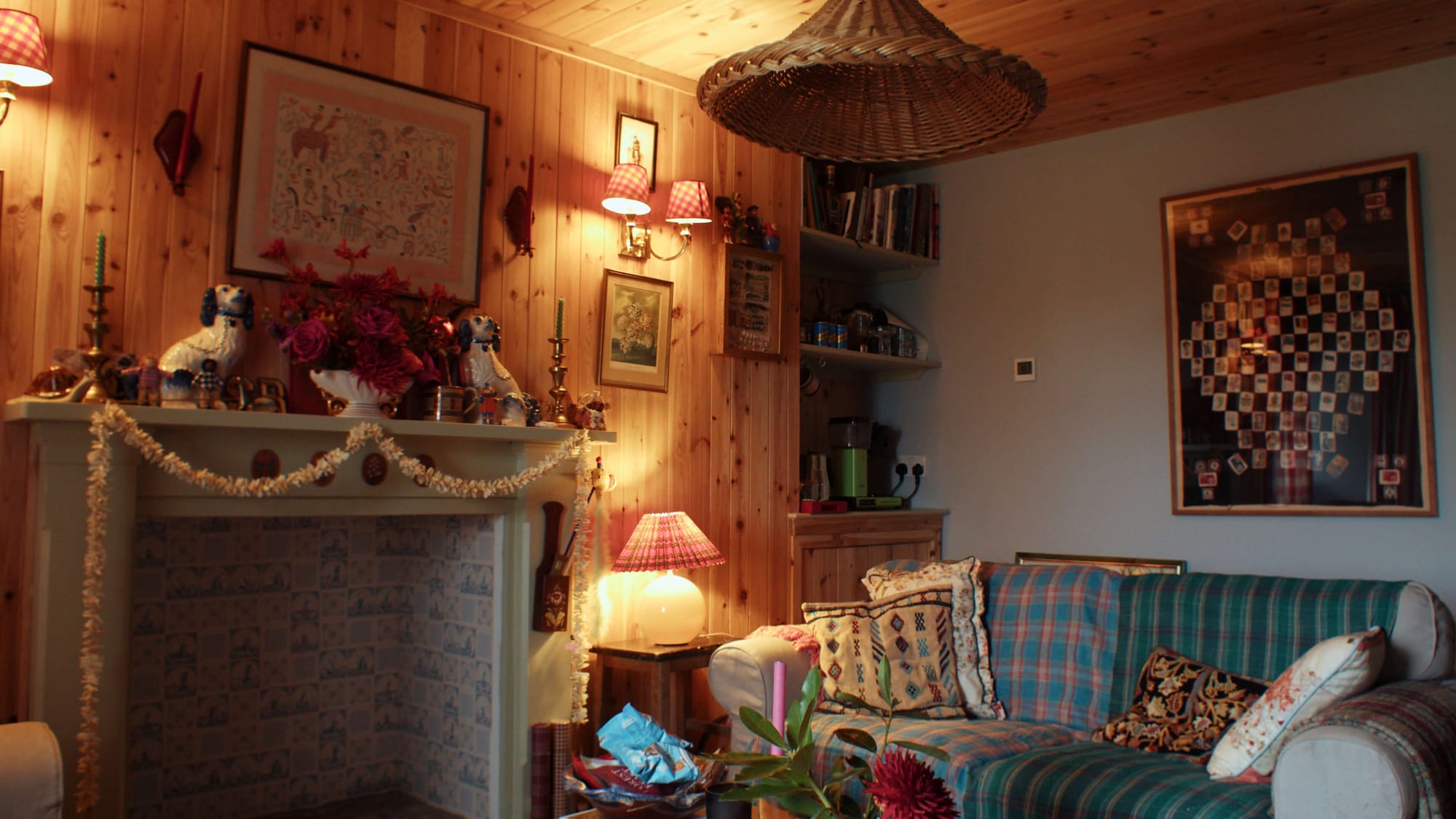 Cosy living room with wood-panelled walls, patterned sofa, fireplace mantel and warm table lamps